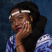 Woman wearing a blue patterned garment against a dark background